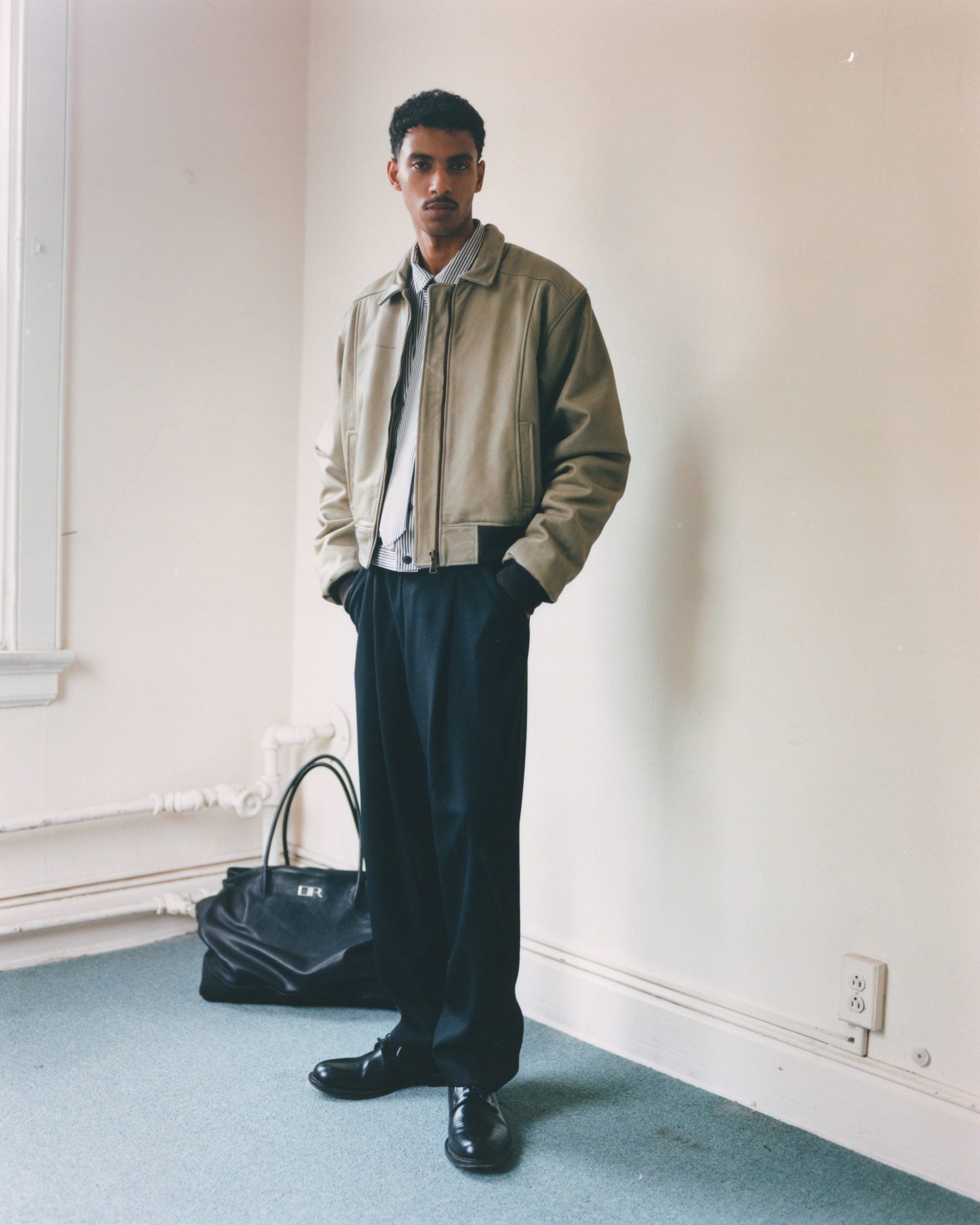 Tan leather blouson and navy pleated trousers